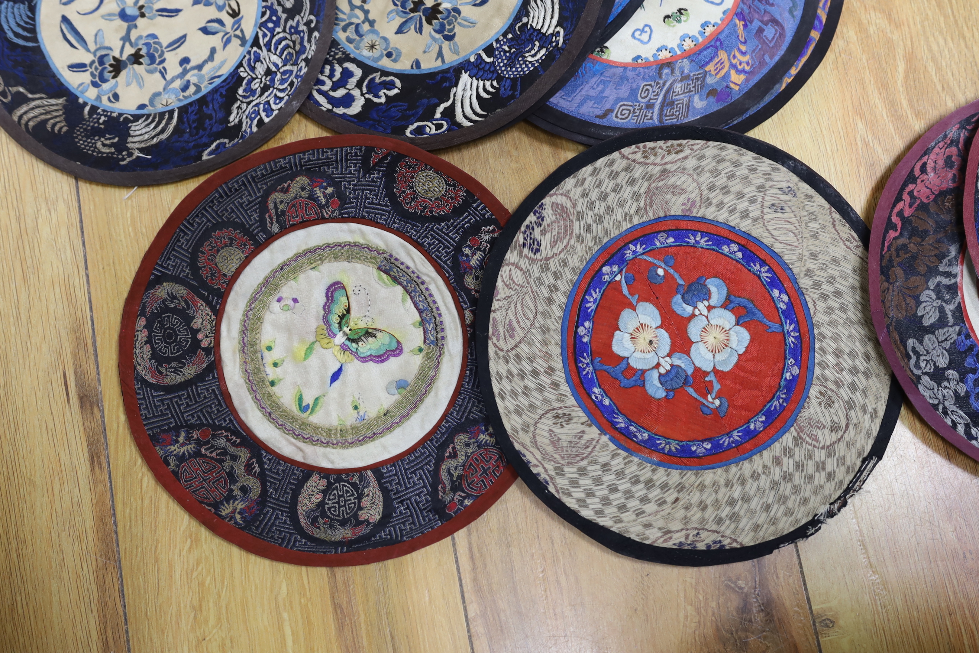 Forty two Chinese embroidered circular mats with damask borders, largest 25cm in diameter